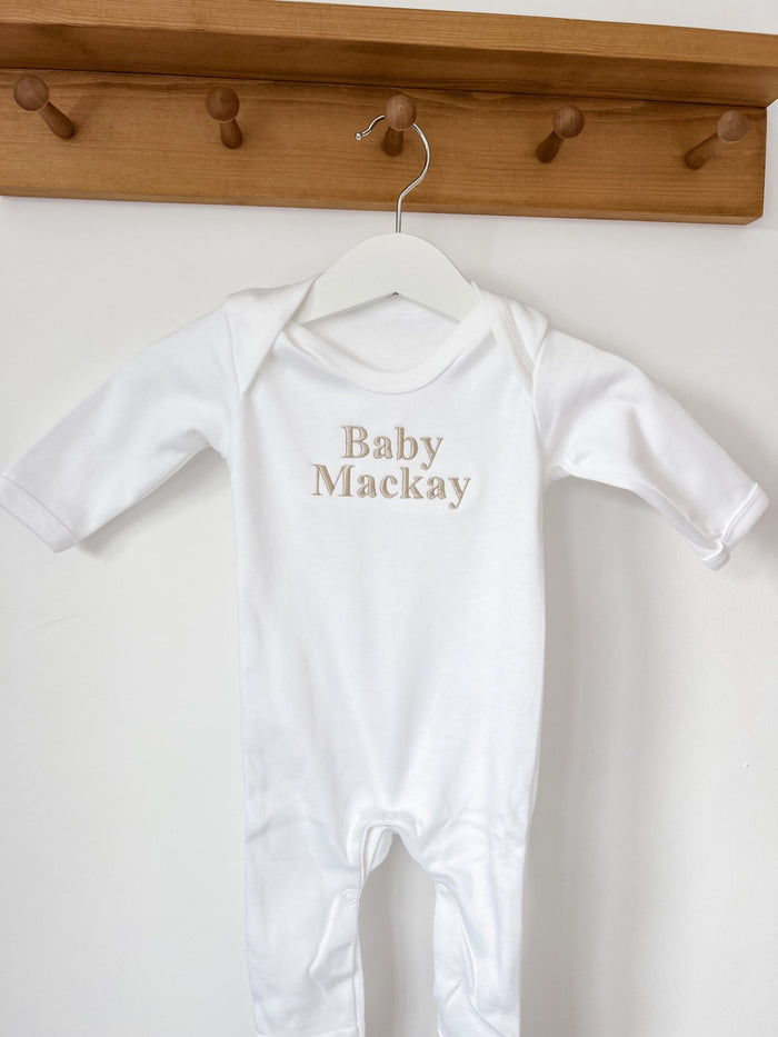 White baby sleepsuit with long cuffs and footed legs, 'Baby Mackay' print