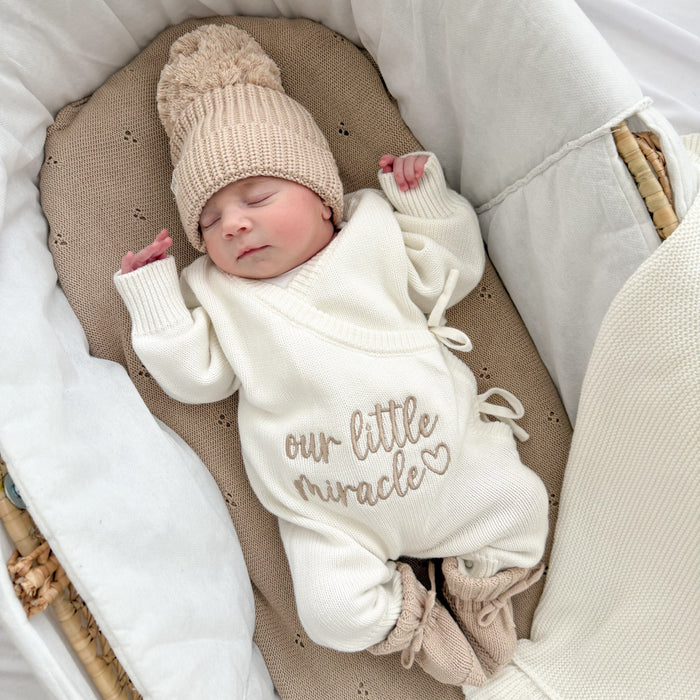 Cream long-sleeve baby romper with “our little miracle” text and drawstring neck ties