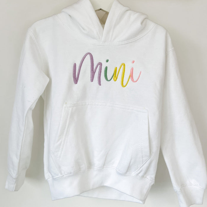 Close-up white hoodie with 'Mini' script embroidery on chest and kangaroo pocket