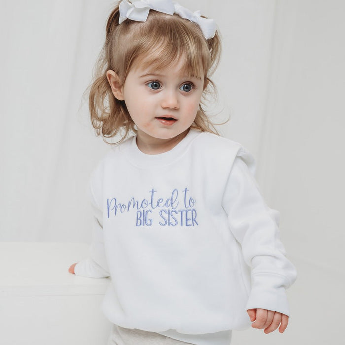 White pullover sweater with "Promoted to BIG SISTER" slogan on the front