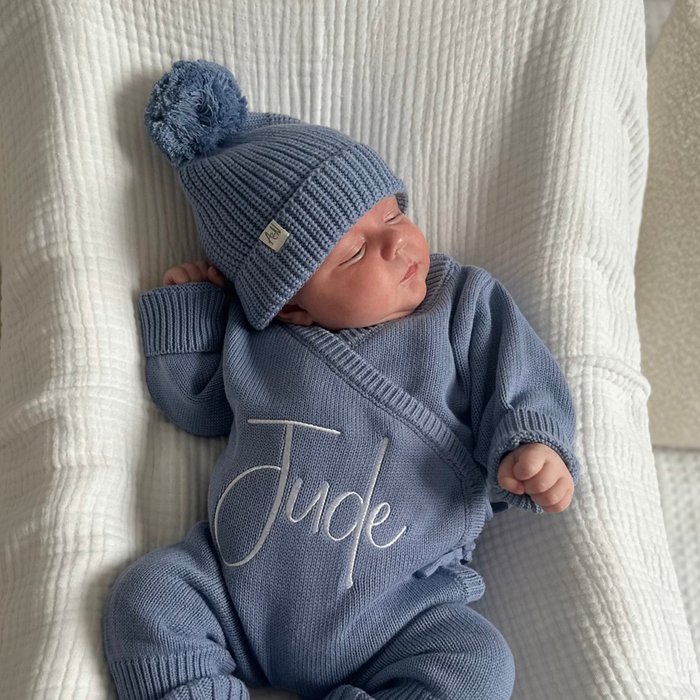 Blue knitted baby hat with pom-pom, worn by baby