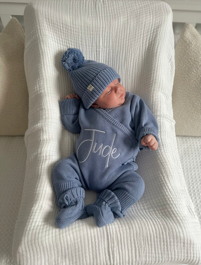 Blue knitted baby booties with tied bow and elastic cuff on blanket
