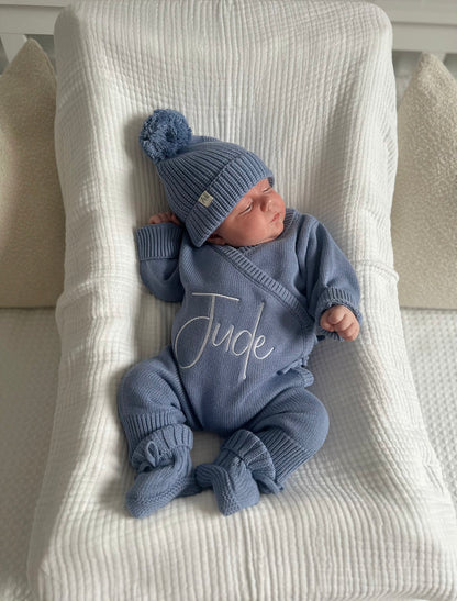 Blue knitted baby booties with tied bow and elastic cuff on blanket