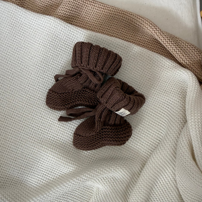 Brown knitted baby booties with ribbed cuffs and bow detail