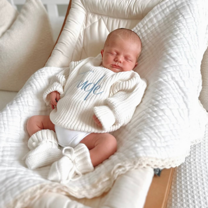 White chunky knitted baby jumper with long sleeves and blue script name on chest