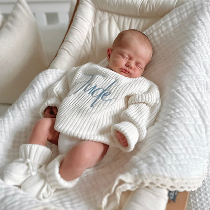 White chunky knitted baby jumper with blue script name and ribbed neckline