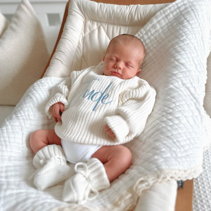 White chunky knitted baby jumper with blue script name and soft ribbed cuffs