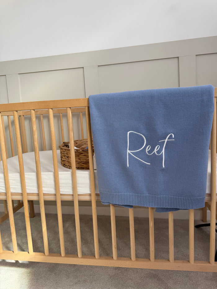 Blue personalised blanket with 'Reef' embroidery, folded and draped