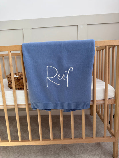 Blue personalised blanket with 'Reef' embroidery, folded over the edge