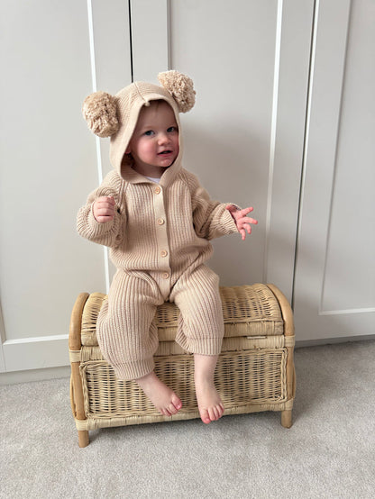 Beige hooded knit romper with pom-pom hat, long sleeves, button front, footed legs