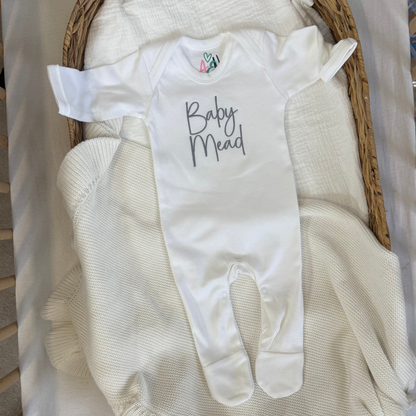 White baby sleepsuit with printed script name and enclosed hand-and-foot sections