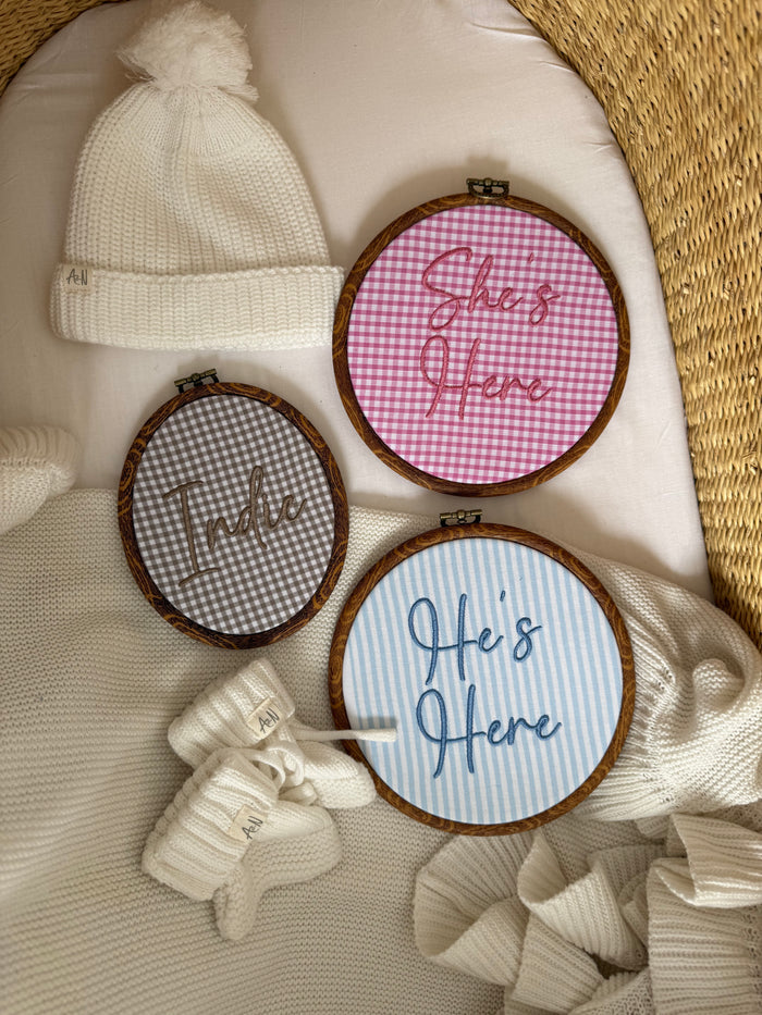 Three round baby announcement signs with stitched names and phrases on gingham fabric circles.