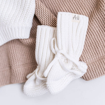 White knitted baby booties with ribbed legs and braided lace ties