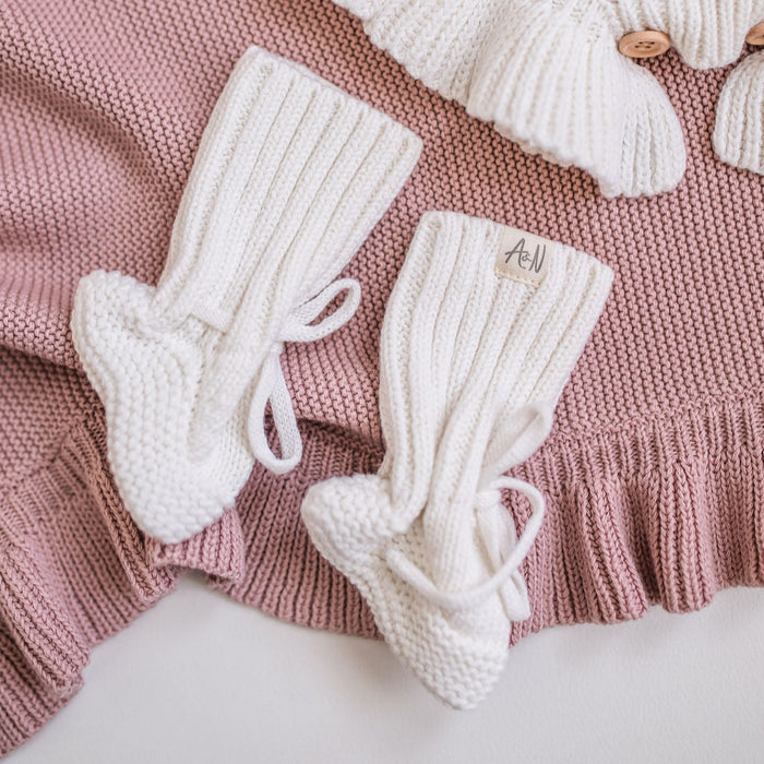 Pair of white knitted baby booties with ribbed cuffs and lace ties