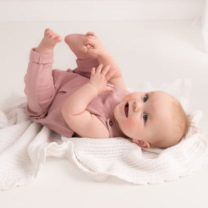 Dusty pink baby embroidered name dungarees with 'Lara' chest embroidery, lying pose