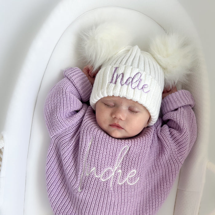 Baby double pom hat on infant, white beanie with fluffy pom and “Indie” embroidery