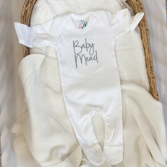 White baby sleepsuit with script name, short sleeves, and snap-fastening feet