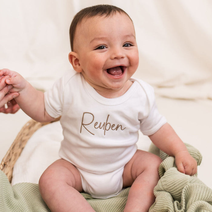 Personalised script baby vest, white with brown Reuben logo-style script