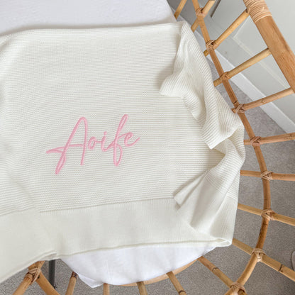 White baby blanket with waffle knit texture and pink “Arfie” name embroidery