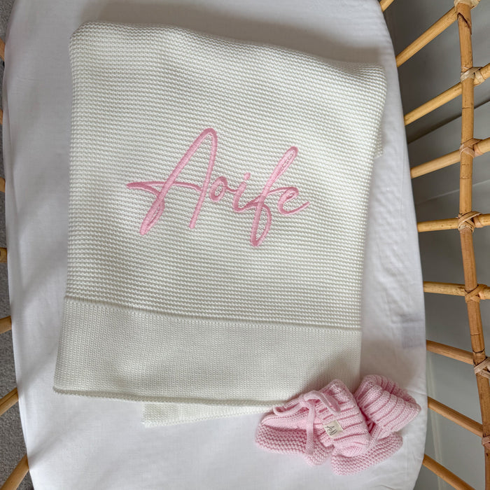 Folded white baby blanket with pink “Arfie” name embroidery and straight edge