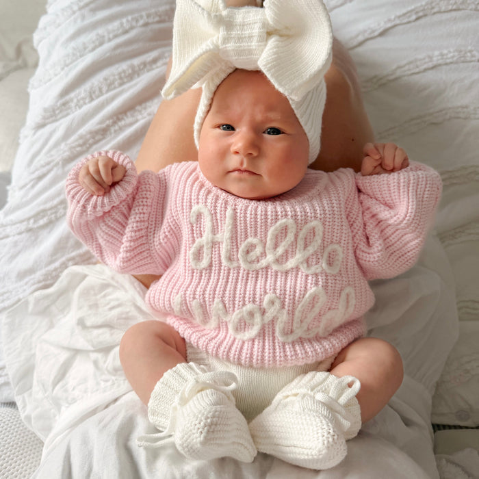 Baby pink chunky knit jumper with "hello world" text, ribbed crew neck and cuffs