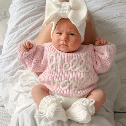 Baby pink chunky knit jumper with "hello world" text, ribbed crew neck and cuffs