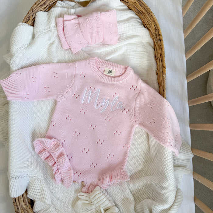 Pink pointelle knitted romper with 'Wolff' embroidery and ruffled leg cuffs