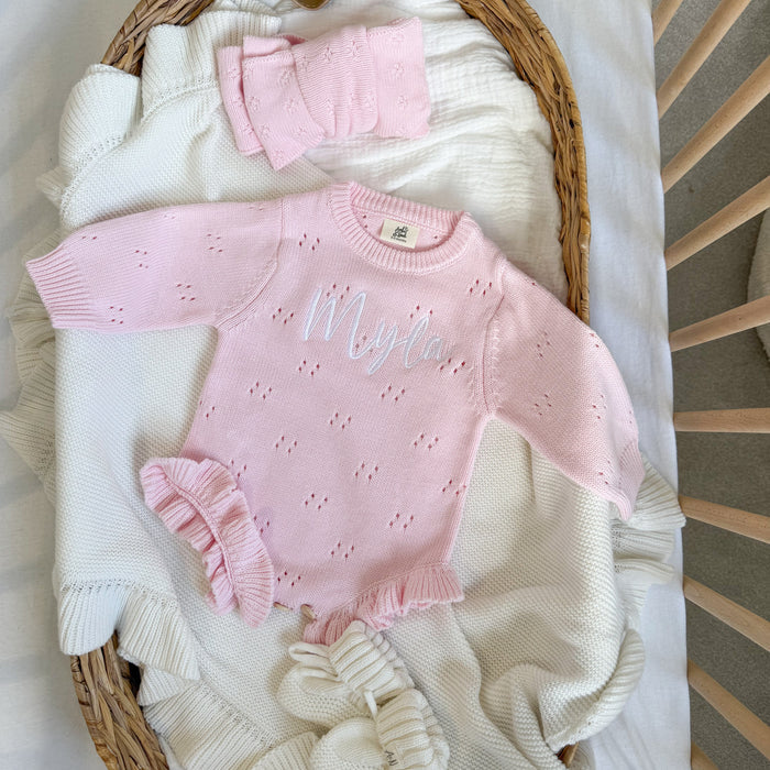Pink pointelle knitted baby romper with 'Wolff' embroidery and ruffled cuffs