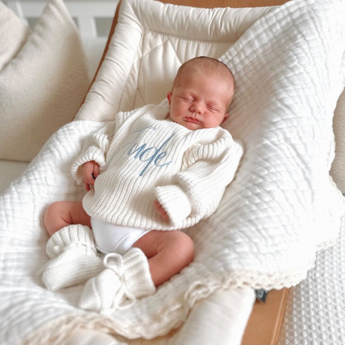 White chunky knitted baby jumper with blue script name and cozy ribbed cuffs