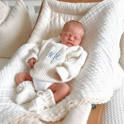 White chunky knitted baby jumper with blue script name and cozy ribbed cuffs