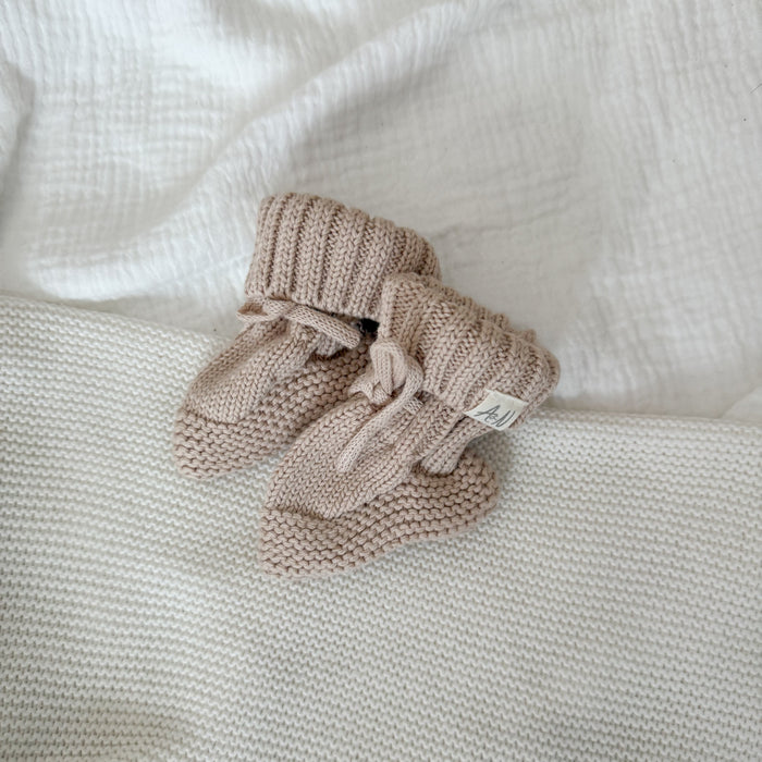 Beige knitted baby booties with ribbed cuff and button bow detail