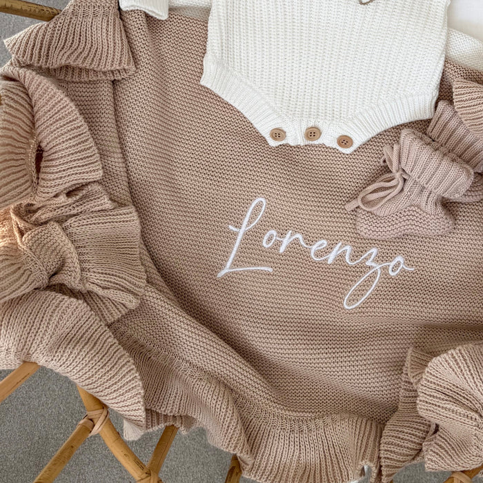 Beige knit blanket close-up with frill edge and 'lorenzo' script