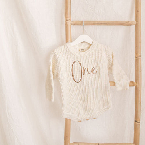 Cream knitted romper, 'One' embroidery at center, long sleeves, crew neckline