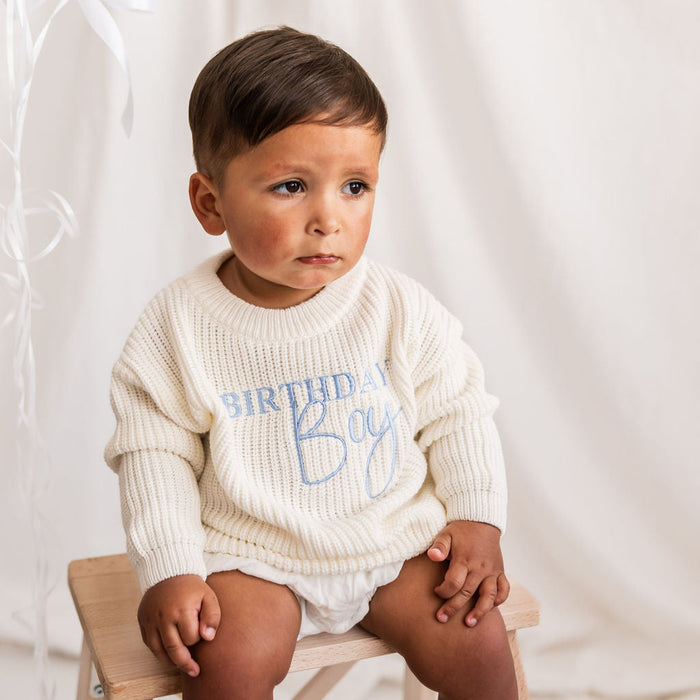 White knitted jumper with blue Birthday Boy print, close-up on child