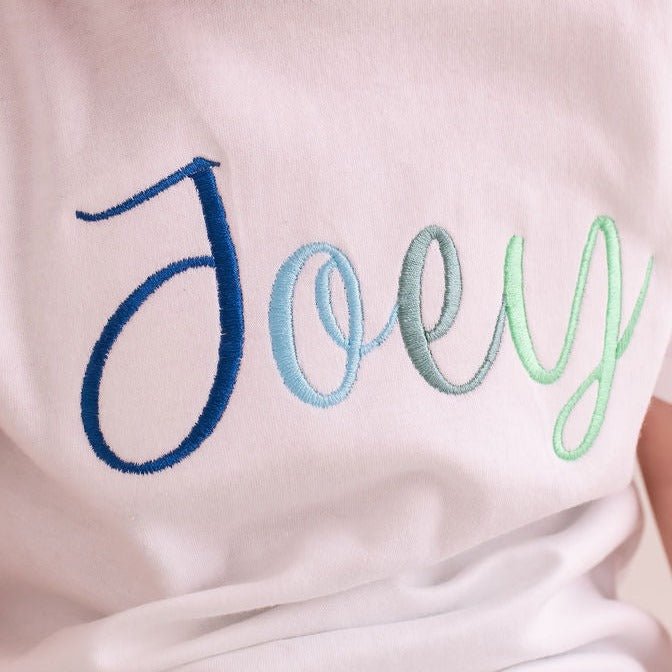 White T-shirt chest close-up with multicolor 'Joey' script embroidery