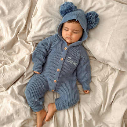Blue knit romper with hood and pom-poms, button front, and 'Ziver' embroidery