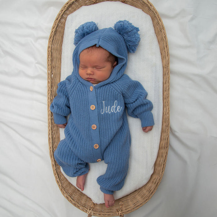 Blue knitted romper with pom-pom hood and “Jude” embroidery, button front