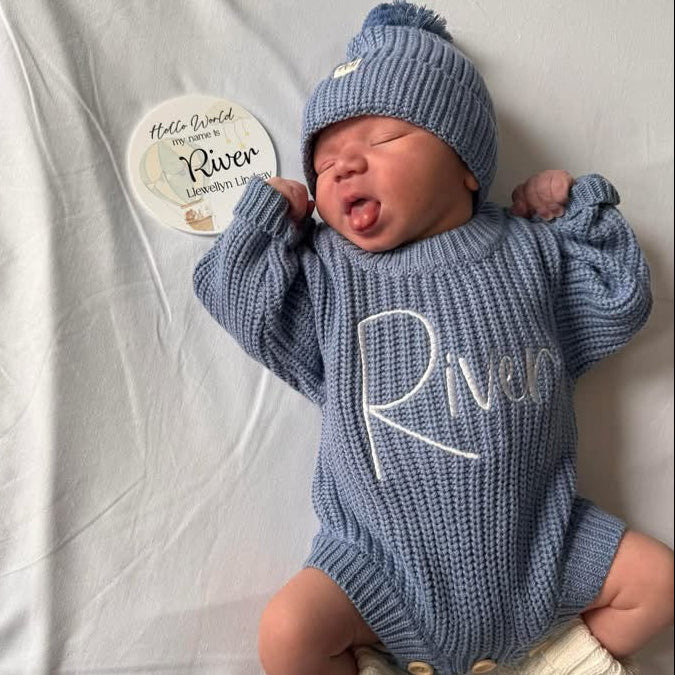 Blue knitted romper with white embroidered “Rivi”, ribbed knit hat and foot snaps