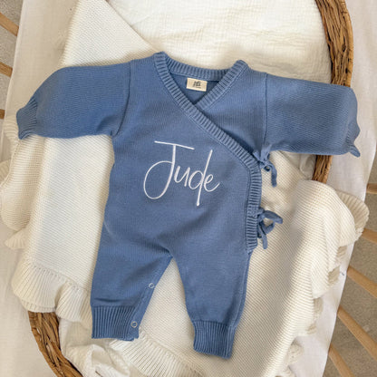 Blue knit long romper with 'Jude' script, V-neck and front button placket.