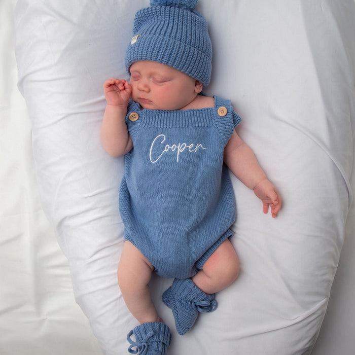 Blue knit personalised romper with button shoulders and matching blue beanie, booties tied