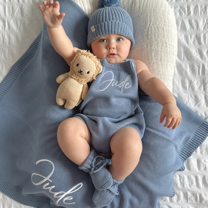 Blue knit personalised romper with embroidered name and matching beanie, teddy plush