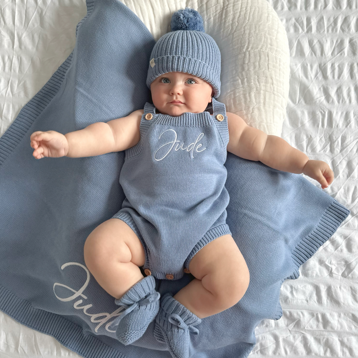 Blue knit personalised romper with embroidered name, matching blue beanie and booties