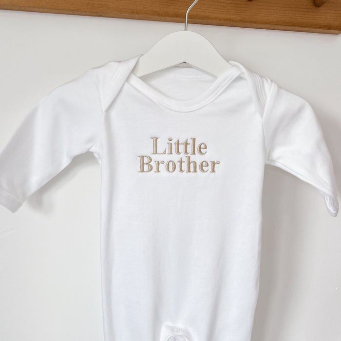 White baby sleepsuit with short sleeves and 'Little Brother' gold chest text