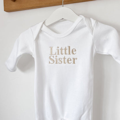 White baby sleepsuit, close-up of long sleeves and Little Sister chest print