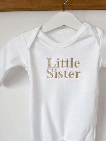 White baby sleepsuit with crew neck and Little Sister front text