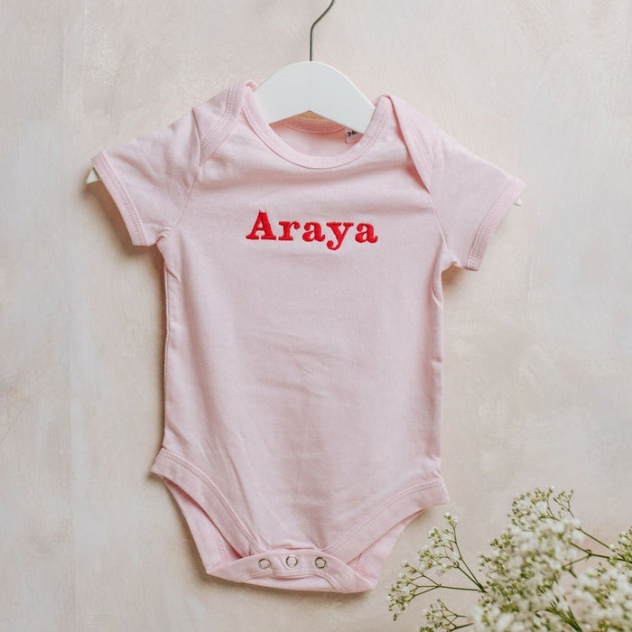 Light pink embroidered baby bodysuit with Araya name on front