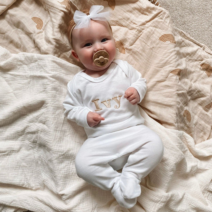White baby romper with “Ivy” embroidered name and long sleeves; bow headband.