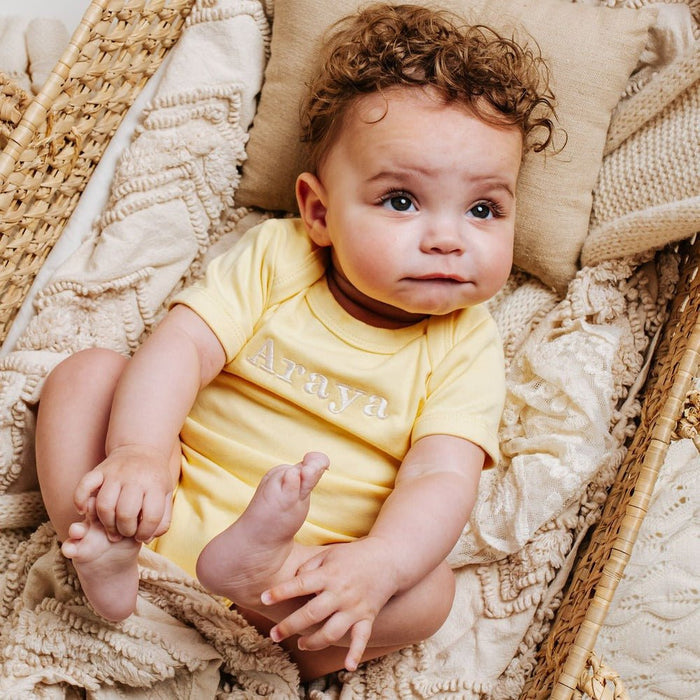 Yellow short-sleeve baby vest with embroidered chest text