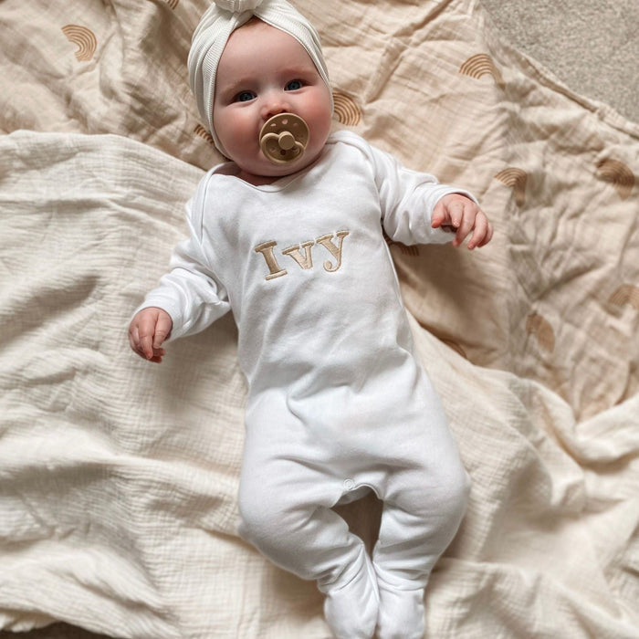 White baby romper with “Ivy” embroidered name and long sleeves; side view.