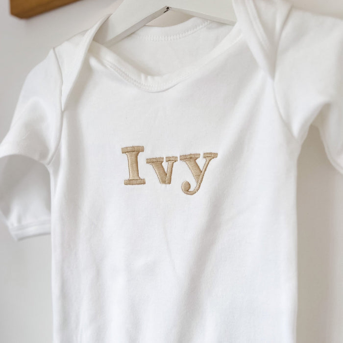 White baby romper close-up with “Ivy” embroidered name on the front.